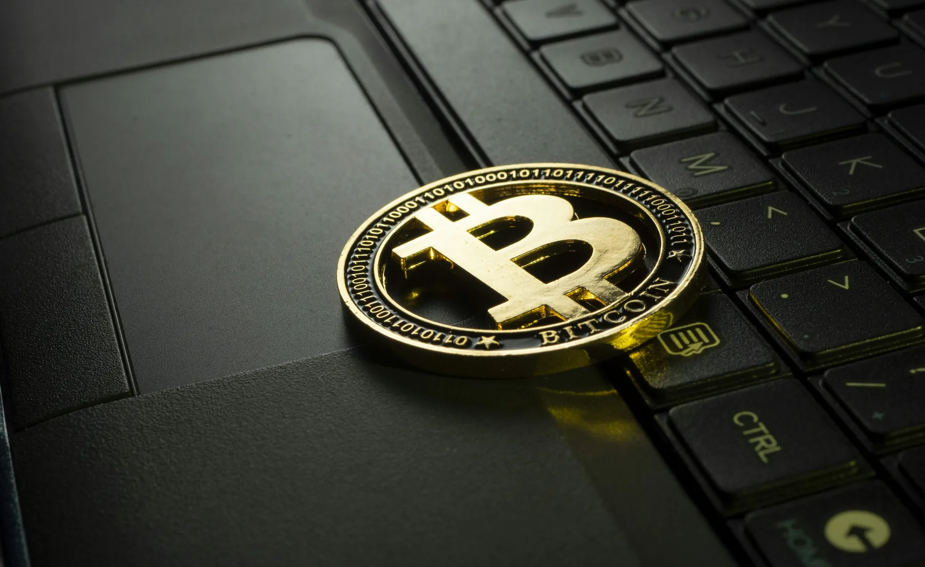 Gold-colored Bitcoin token resting on a computer keyboard
