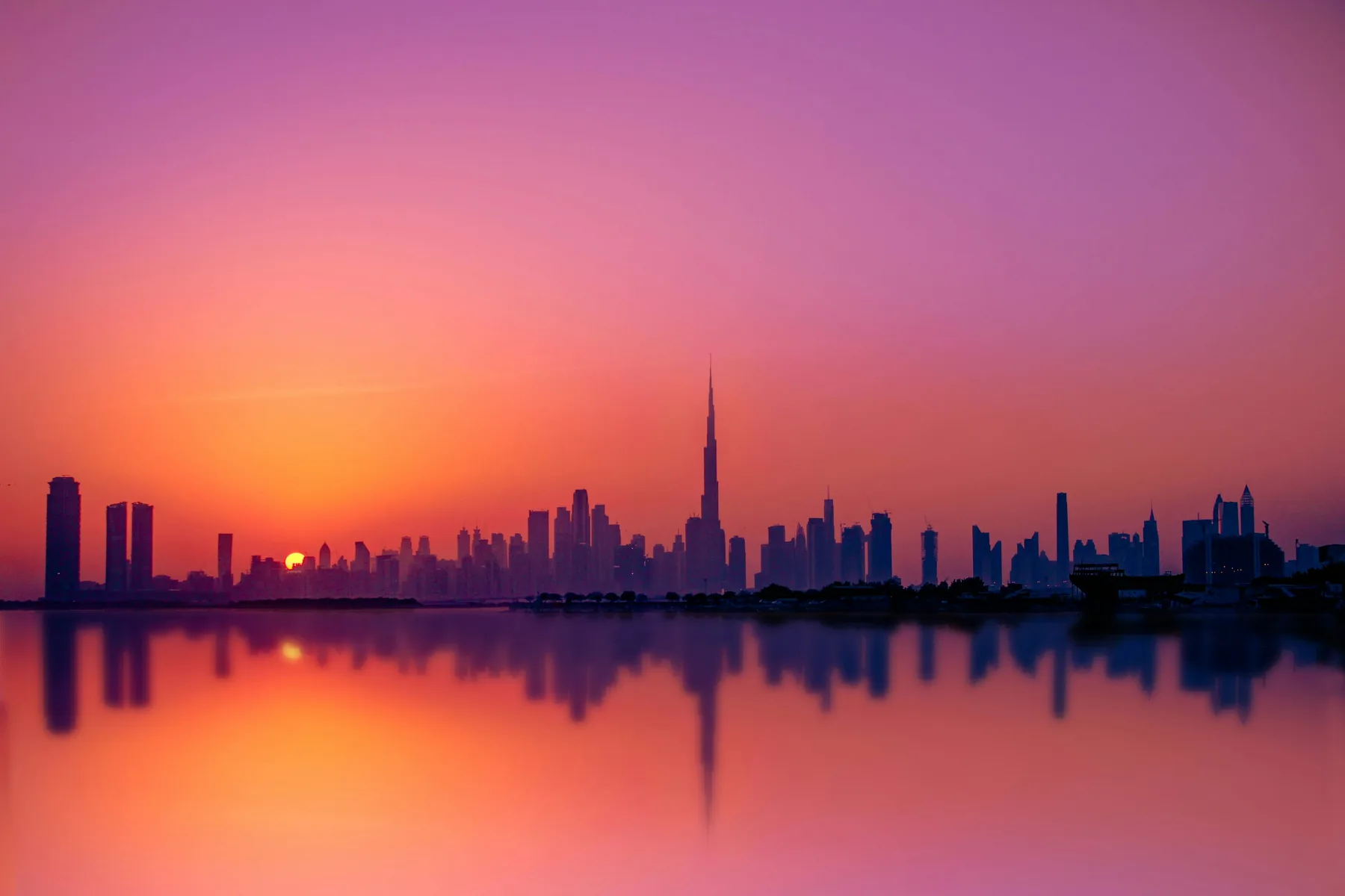 Dubai skyline at sunset reflected across the water